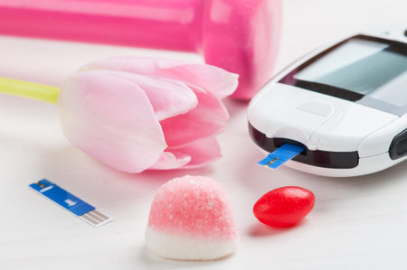 Pink dumbbell, sweets and glucose meter, concept for diabetes, lifestyle and healthy life