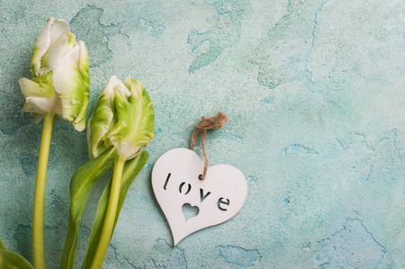 White and green tulip couple with wooden heart on turquoise concrete rustic background. Lifestyle compisition for holidayの写真素材