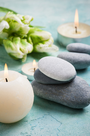 Stones SPA treatment composition with lit candles and flowers on blue concrete backgroundの写真素材