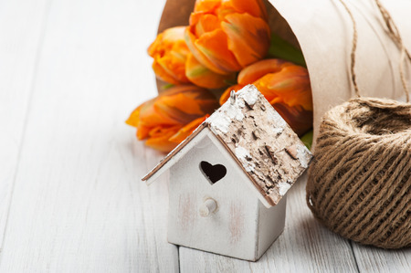 Easter greeting card with orange tulips, wooden heart shape bird house and twine. Space for text. country cottage rustic style. valentine's day, romantic, love conceptの写真素材