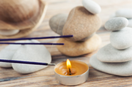 Purple aroma sticks fuming on the wooden background with stacks of pebbles. Aromatherapy accessoriesの写真素材