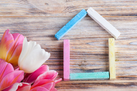 House made of multicolor chalks with tulips on shabby wooden backgroundの写真素材