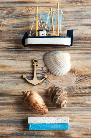Seashells, wooden anchor and toy boat on shabby backgroundの写真素材