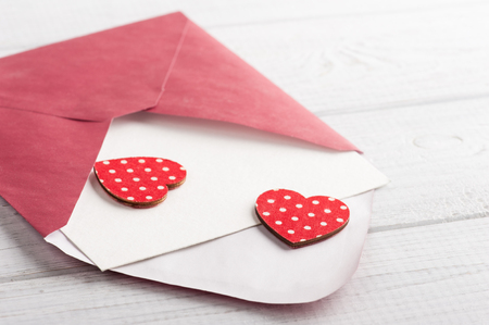 Red envelope with empty paper and red hearts on white tableの写真素材