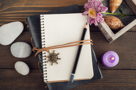 Top view of open blank notebook, pebbles, lit candle, flower, shells. Travel and adventure concept, journey diaryの写真素材