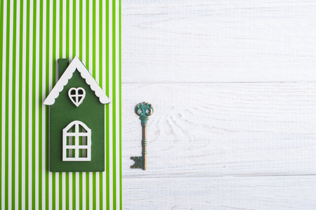 Green wooden house and key on a striped background. Top viewの写真素材