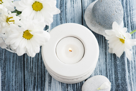 Candle and pebbles, and daisy flowers over shabby wooden background, top viewの写真素材