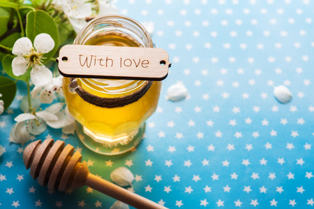 Honey with blossoms and wooden spoon on blue stars backgroundの写真素材