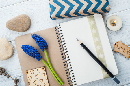 Gift Box with Tag Love and open notebook. Wooden background, lit candle, pebbles, blue flowers.の写真素材