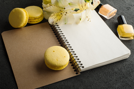 Blank notebook, yellow macaroons, nail polish on concrete background. Copy spaceの写真素材