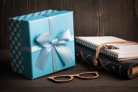 Blue gift box with ribbon and note books on dark wooden background. Father's day concept の写真素材