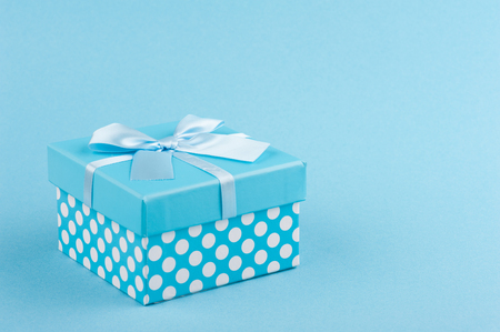Blue gift box with ribbon on paper background.の写真素材