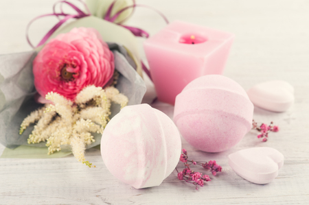 SPA composition with pink bath bombs, ranunculus, heart on white wooden background. Top view, copy spaceの写真素材