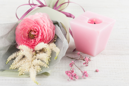 Bouquet with ranunculus and pink lit candleの写真素材