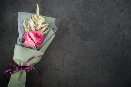 Bouquet with ranunculus, leafs, twigs on black concrete background. Concept for workshop or...