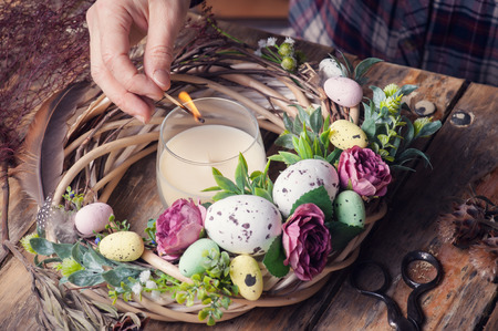 Making of Easter DIY wreath with eggs and flowers, composition on rustic wooden tableの写真素材