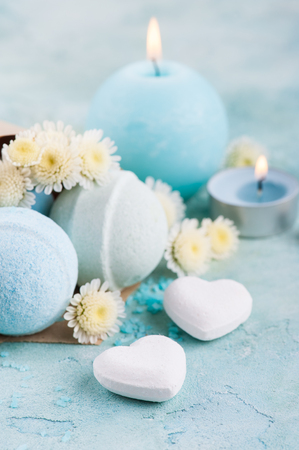Spa products with bath bombs, sea salt and flowers on blue background. Beauty treatment concept with lit aroma candleの写真素材