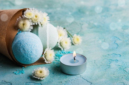 Spa products with bath bombs, sea salt and flowers on blue background. Beauty treatment concept with lit aroma candleの写真素材