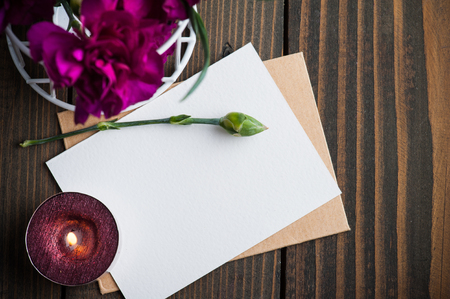 Bunch of purple carnations, blank card and lit candles on rustic vintage wooden background with copy spaceの写真素材