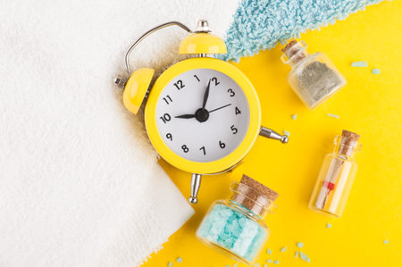 Bright summer holiday background with alarm clock, sea salts and nautical decor on yellow desk top...
