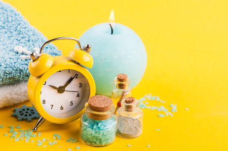 Bright summer holiday background with alarm clock, sea salts and nautical decor on yellow desk top viewの写真素材