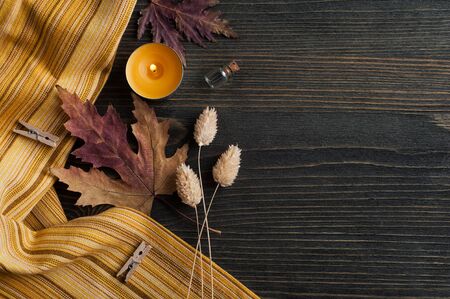 Dark wooden background with autumnal leaves and lit candles, top view with copy spaceの写真素材