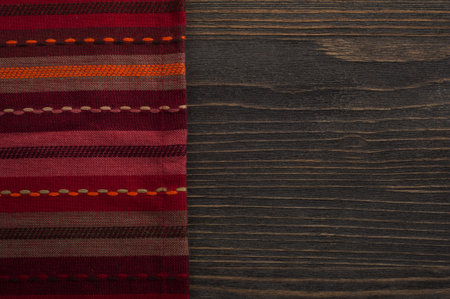 Dark wooden background with red napkin, top view with copy space