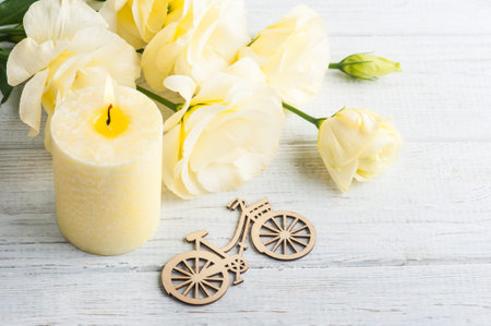 Wooden bike with yellow lisianthus flowers and lit candle
