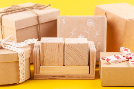 Empty blank wooden calendar and kraft gift boxes on yellow. Mock up for idea of celebration, sale or...
