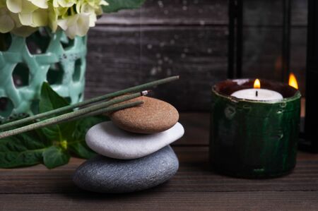 Green aroma sticks in Spa still life on dark wooden background with hortensia flowers and lit candles. Pile of pebblesの写真素材