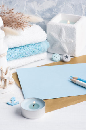 Empty envelope with blue decor and lit candle as decoration. Holiday or wedding planner concept with...