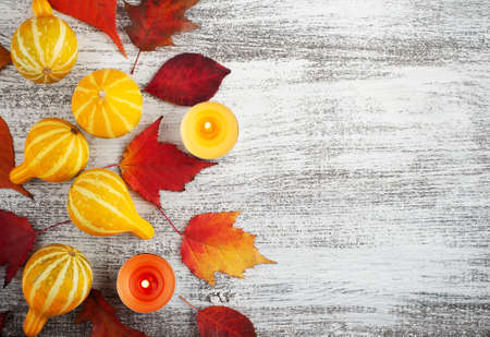 Orange red falling leaves frame on rustic wooden table. Thanksgiving or halloween set with copy spaceの写真素材