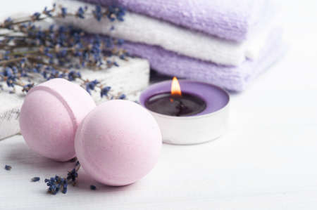 Pink aroma bath bombs in spa composition with dry lavender flowers and towels. Aromatherapy arrangement, zen still life with lit candleの写真素材