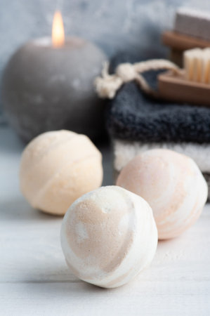 Spa composition with bath bombs, body brushes and towels. Aromatherapy arrangement, zen still life on concrete blue gray background with lit candleの写真素材