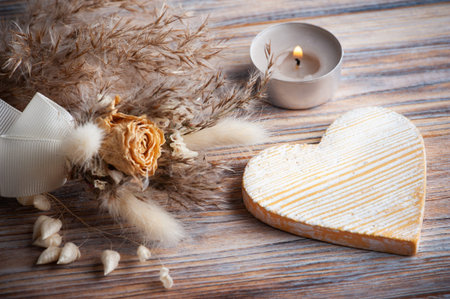 Yelow decorative heart, lit aroma candle and dry flowers on rustic background. Greeting card for...