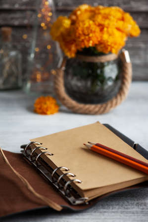 Empty open craft notebook and orange chrysanthemum flowers on rustic background. Greeting card with copy space for your textの写真素材