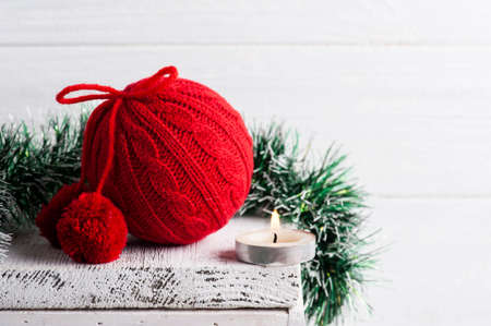Red knit Christmas ball and decoration with lit candle in white scandinavian interior. Copy space for gretingの写真素材