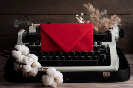 Russian Typewriter close up and dry flowers with red envelope. Valentines concept, vintage toned and kraft paperの写真素材