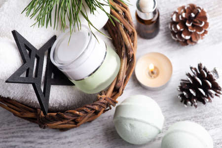 Beauty product in basket in Christmas SPA composition with pine tree branches and stars, lit candleの写真素材