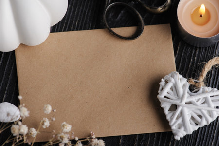 Mock-up card with craft brown envelope and heart and dry flowers on black wooden background. Still life with copyspace for text. Autumnal greeting card and advertismentの写真素材