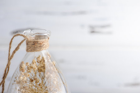 Dry flowers in glass vase in Scandinavian Style with copy space. Fall decoration in white beige colors on white rustic wooden background. Autumnal still lifeの写真素材