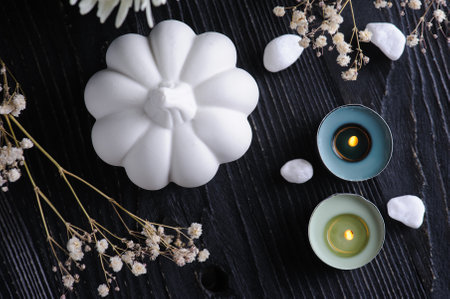 Fall decoration with white pumpkins and lit candles on black wooden background. Still life top view. Autumnal greeting card and advertismentの写真素材