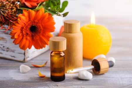 Essential oil in reusable bottles on wooden background with orange flowers. Natural organic spa with eco friendly packagingの写真素材
