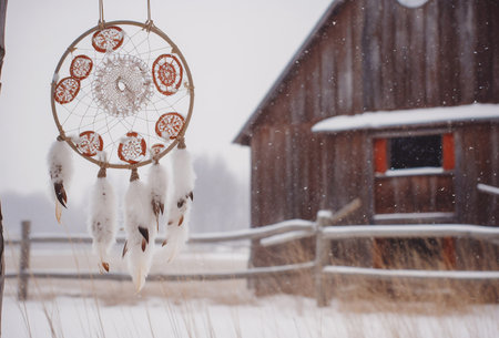 Retro dream catchers hanging in snow, barn on background. Generative AIの素材