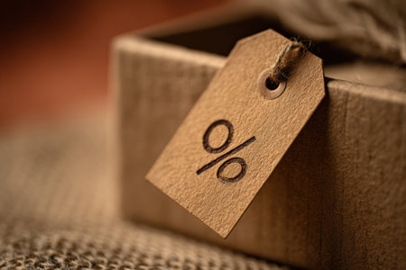Close-up of a blank kraft paper tag tied with string on a wrapped gift box. Minimal rustic style for branding, labels, pricing, packaging, product presentation, or holiday designの素材