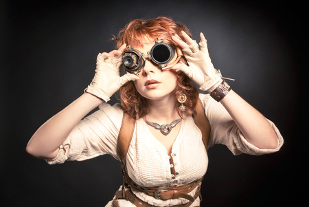 Beautiful redhair steampunk woman looking over her gogglesの写真素材