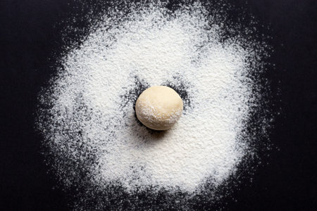 dough for making bread or pizza on a black background, top view