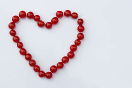 red cherry tomatoes in the shape of a heart on a white background. Flat lay.の写真素材