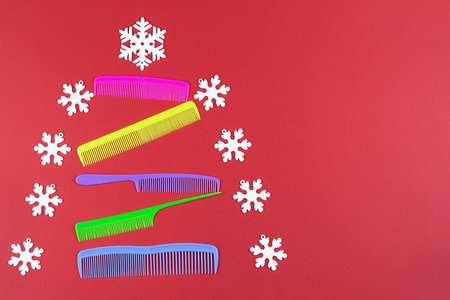 Beautiful Christmas tree made of multi-colored combs and snowflakes on a red background. Christmas...