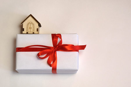 Little model of a wooden house and gift box on a white background.の写真素材